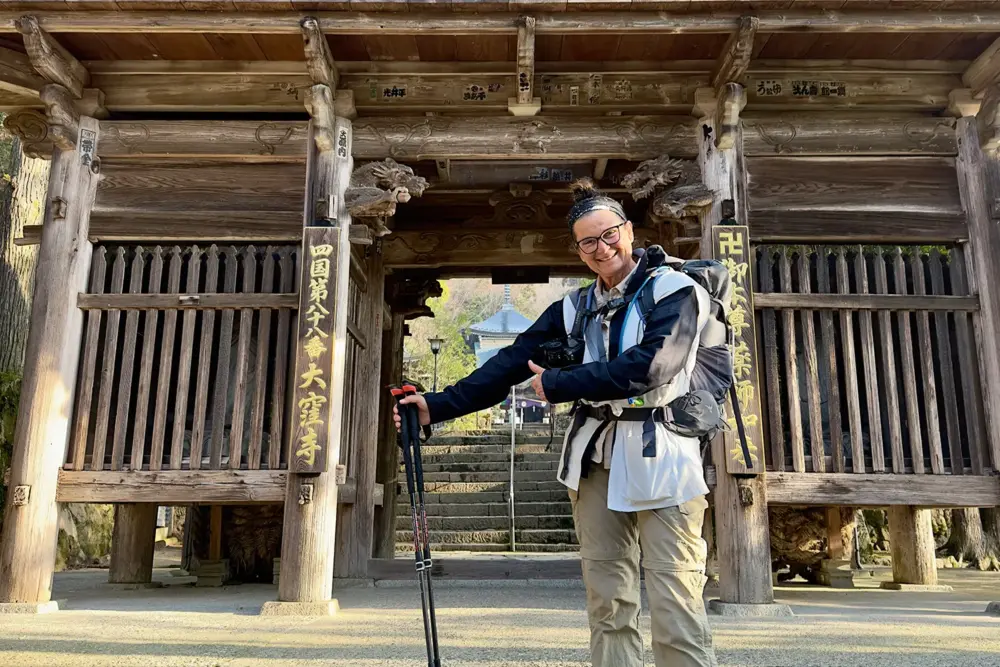 Shikoku Pilgerreise und Fotografie: 950 Kilometer, 88 Tempel, ein Buch 2 Shikoku Pilgerreise Fotografie: Marion Rockstroh-Kruft mit Rucksack und Wanderstöcken vor dem Tor von Tempel 88, Japan